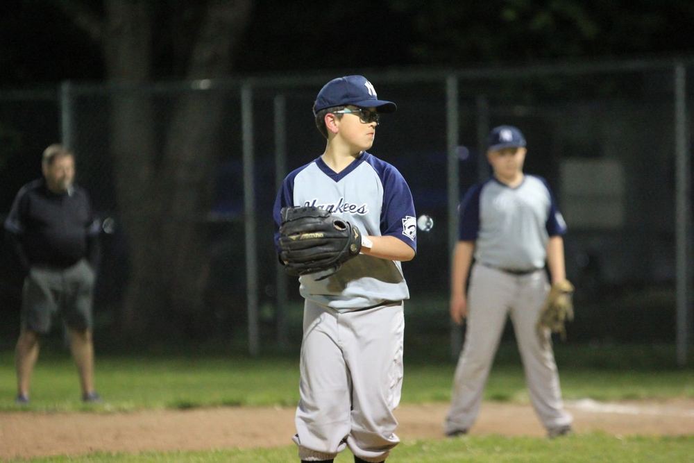 A Winchester Little League baseball player standing ready with his glove during a game.