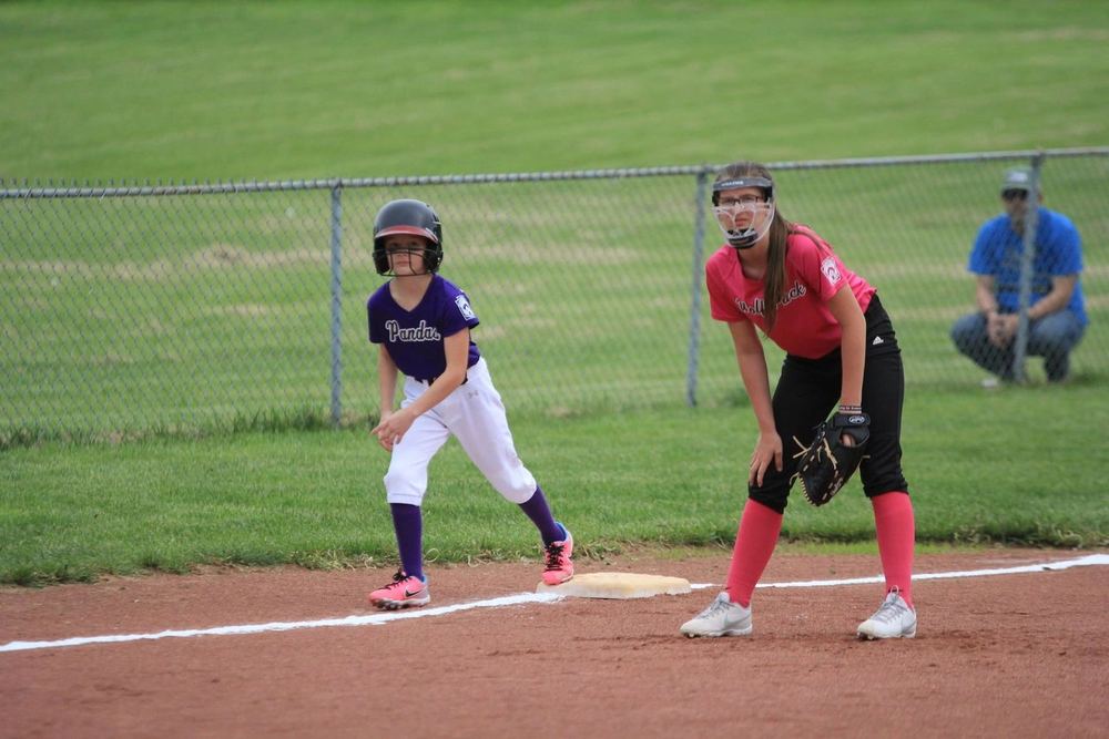 Two Winchester Little League softball players at a base during a game, one leading off and one covering.