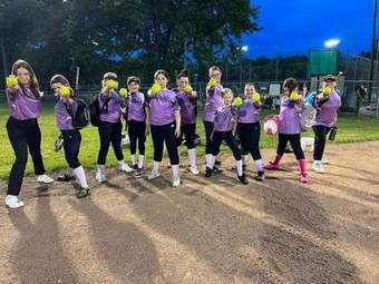 A Winchester Little League softball team lined up on the field under the lights in 2023.