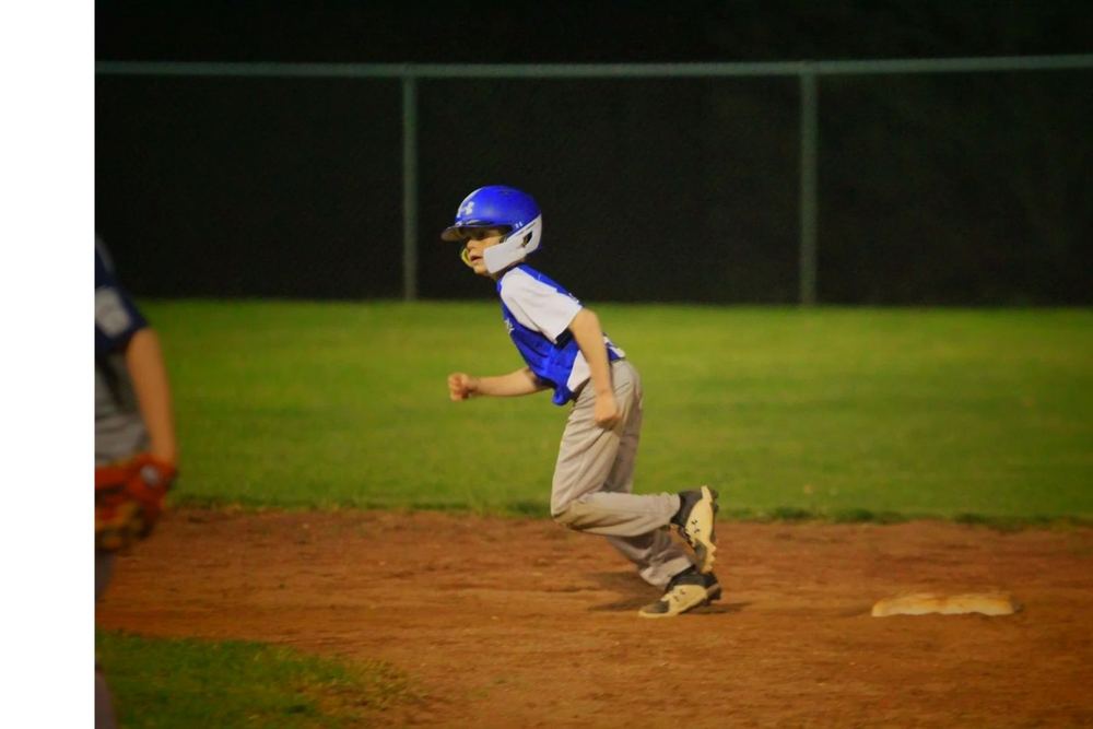 A young Winchester Little League baseball player running the bases in the evening light.